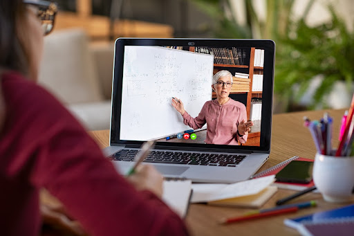 A student watches an online lesson on a laptop